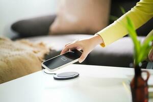 Charging mobile phone battery with wireless charging device in the table. Smartphone charging on a charging pad. Mobile phone near wireless charger Modern lifestyle technology concept. photo