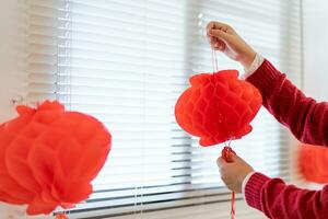 Asian Woman holding red Chinese new year lantern while decorated flat putting traditional pendant to the Chinese New Year Celebrations for good luck. chinese word means blessing. photo