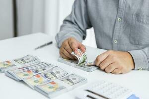 Businessman analyzing investment charts and pressing calculator buttons over documents. Accounting Concept. photo