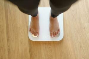 perder peso. grasa dieta y escala pies en pie en electrónico escamas para peso control. medición instrumento en kilogramo para dieta. foto