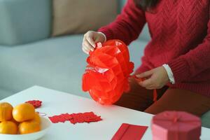 Asian Woman holding red Chinese new year lantern while decorated flat putting traditional pendant to the Chinese New Year Celebrations for good luck. chinese word means blessing photo