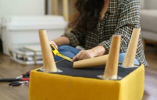 Asian Woman self repairs furniture renovation using equipment to diy repairing furniture sitting on the floor at home photo