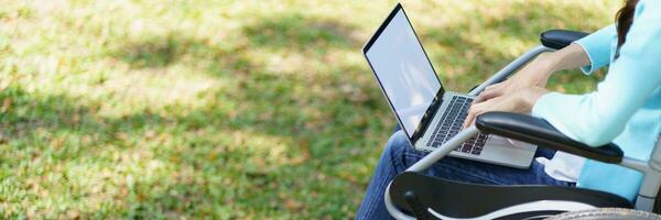 Young asian woman in wheelchair working with laptop photo