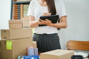 asiático mujer preparando paquete entrega caja Envío para compras en línea entrega correo Servicio personas y envío concepto foto