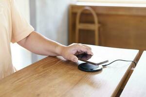 cargando móvil teléfono batería con inalámbrico cargando dispositivo en el mesa. teléfono inteligente cargando en un cargando almohadilla. móvil teléfono cerca inalámbrico cargador moderno estilo de vida tecnología concepto. foto