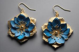 Pair of gold earrings with blue flowers on a gray background. photo