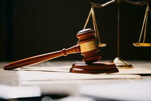 Justice and law concept.Male judge in a courtroom with the gavel, working with, computer and docking keyboard, eyeglasses, on table in morning light photo