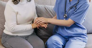 Homecare nursing service and elderly people cardiology healthcare. Close up of young hispanic female doctor nurse check mature caucasian man patient heartbeat using stethoscope during visit photo