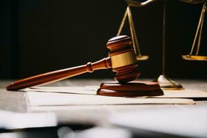 Justice and law concept.Male judge in a courtroom with the gavel, working with, computer and docking keyboard, eyeglasses, on table in morning light photo