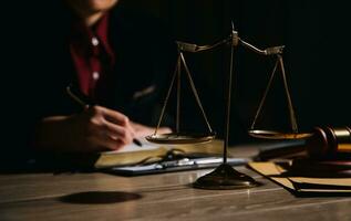 Justice and law concept.Male judge in a courtroom with the gavel, working with, computer and docking keyboard, eyeglasses, on table in morning light photo