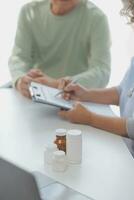 A health visitor with tablet explaining a senior woman how to take pills. photo