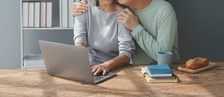 Embraced mature couple surfing the Internet on laptop at home photo