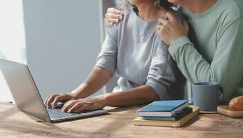 Embraced mature couple surfing the Internet on laptop at home photo