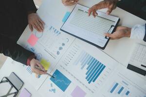 Financial analysts analyze business financial reports on a digital tablet planning investment project during a discussion at a meeting of corporate showing the results of their successful teamwork. photo