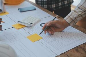 reunión de trabajo en equipo de ingenieros, trabajo de dibujo en la reunión de planos para el trabajo del proyecto con un socio en la construcción de modelos y herramientas de ingeniería en el concepto de sitio de trabajo, construcción y estructura. foto