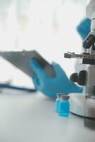 Professional lab. Amazing longhaired medical worker wearing uniform while using microscope during research photo