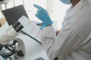Professional lab. Amazing longhaired medical worker wearing uniform while using microscope during research photo