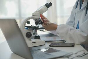 Professional lab. Amazing longhaired medical worker wearing uniform while using microscope during research photo