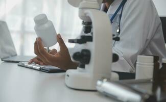Professional lab. Amazing longhaired medical worker wearing uniform while using microscope during research photo