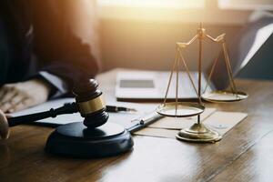 Justice and law concept.Male judge in a courtroom with the gavel, working with, computer and docking keyboard, eyeglasses, on table in morning light photo