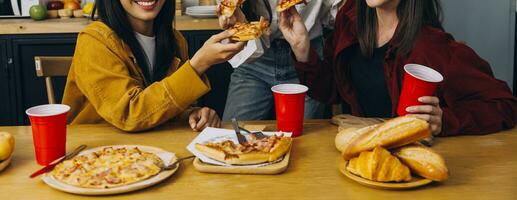 Laughing group of diverse young woman hanging out at home together and eating pizza photo