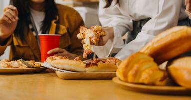 Laughing group of diverse young woman hanging out at home together and eating pizza photo