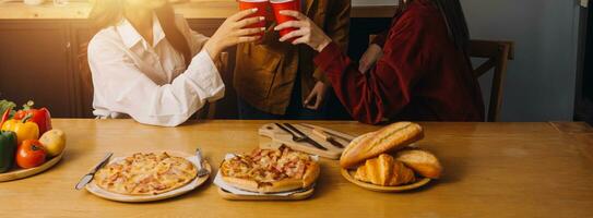 Laughing group of diverse young woman hanging out at home together and eating pizza photo