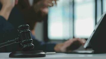 Justice and law concept.Male judge in a courtroom with the gavel, working with, computer and docking keyboard, eyeglasses, on table in morning light video