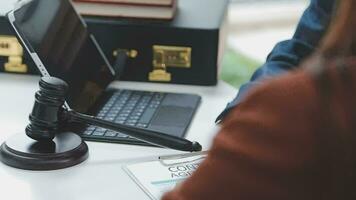 concetto di giustizia e diritto. giudice maschio in un'aula di tribunale con il martelletto, lavorando con computer e tastiera docking, occhiali, sul tavolo alla luce del mattino video