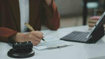 concetto di giustizia e diritto. giudice maschio in un'aula di tribunale con il martelletto, lavorando con computer e tastiera docking, occhiali, sul tavolo alla luce del mattino video