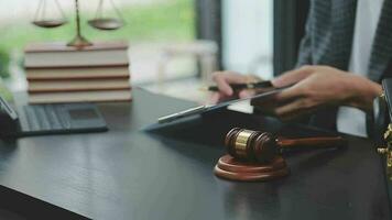 Justice and law concept.Male judge in a courtroom with the gavel, working with, computer and docking keyboard, eyeglasses, on table in morning light video