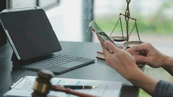 concetto di giustizia e diritto. giudice maschio in un'aula di tribunale con il martelletto, lavorando con computer e tastiera docking, occhiali, sul tavolo alla luce del mattino video