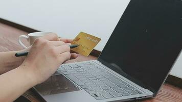 en línea pago, joven mujer participación crédito tarjeta y mecanografía en ordenador portátil video