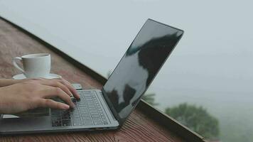 joven negocio mujer trabajando a el computadora en café en el roca. joven niña reductor de marcha trabajando a un ordenador portátil a puesta de sol o amanecer en el parte superior de el montaña a el mar, trabajando día. video