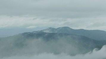 montaña rango con visible siluetas mediante el Mañana azul niebla. video