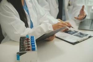 un médico confiado sostiene un frasco de pastillas y escribe mientras habla con un paciente mayor y revisa su medicación en la oficina. foto