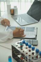 Confident doctor man holding a pill bottle and writing while talking with senior patient and reviewing his medication at office room. photo