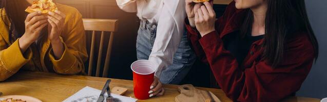 Group of young friends eating pizza at home and having fun photo