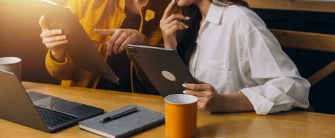 Asian Young colleague business presents and explains and using laptop computer in an office. Teamwork, coworker cooperation, financial marketing team, or corporate business employee concept. photo