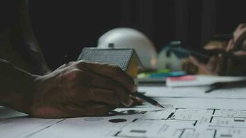 costruzione e struttura concetto di ingegnere Lavorando disegno su planimetria incontro per progetto Lavorando con compagno su modello edificio e ingegneria utensili nel Lavorando luogo, costruzione concetto. video