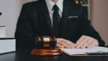 Business and lawyers discussing contract papers with brass scale on desk in office. Law, legal services, advice, justice and law concept picture with film grain effect video