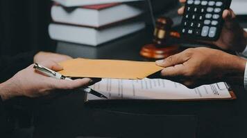 Business and lawyers discussing contract papers with brass scale on desk in office. Law, legal services, advice, justice and law concept picture with film grain effect video