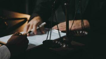 Business and lawyers discussing contract papers with brass scale on desk in office. Law, legal services, advice, justice and law concept picture with film grain effect video