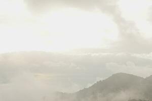 Mountain range with visible silhouettes through the morning blue fog. photo