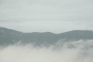 Mountain range with visible silhouettes through the morning blue fog. photo