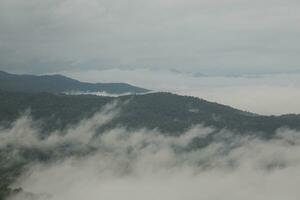 Mountain range with visible silhouettes through the morning blue fog. photo