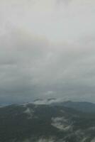 Mountain range with visible silhouettes through the morning blue fog. photo