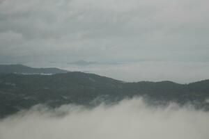 Mountain range with visible silhouettes through the morning blue fog. photo