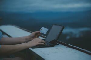 online payment, young woman holding credit card and typing on laptop photo