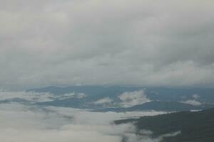 Mountain range with visible silhouettes through the morning blue fog. photo